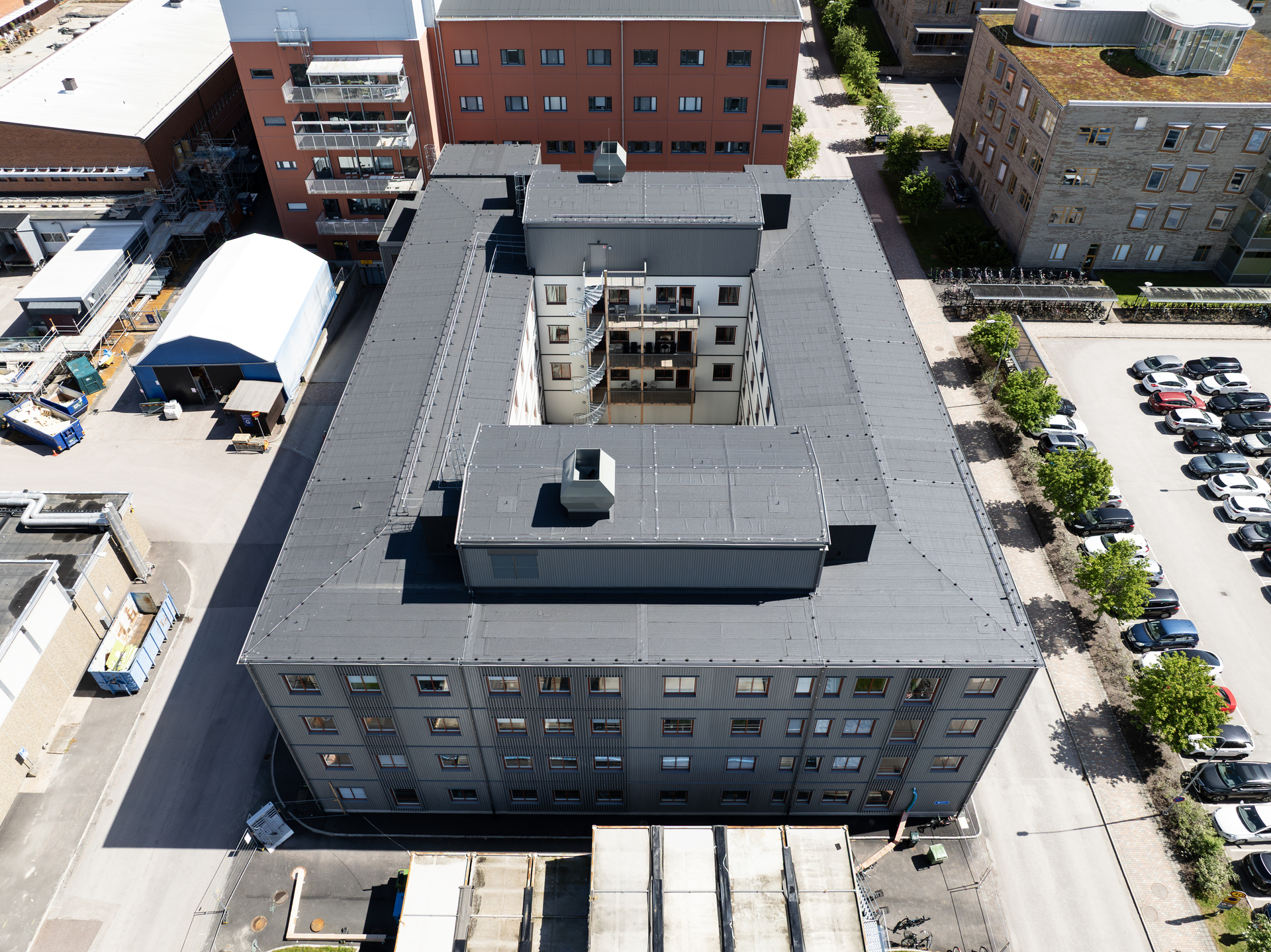 Flygfoto uppifrån av kontorsmoduler från Expandia vid Centralsjukhuset i Karlstad. Den fyravånings modulbyggnaden med sluten kvartersform och innergård syns ovanifrån, omgiven av sjukhusets befintliga byggnader, parkeringsytor och grönska. Bilden visar hur Expandias kontorsmoduler är integrerade i sjukhusområdet och skapar funktionella, flexibla arbetsmiljöer i direkt anslutning till vårdverksamheten.