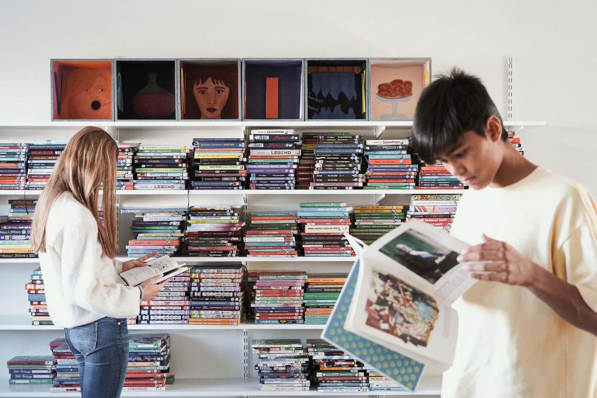 Elever läser och väljer böcker i skolbibliotek vid Nyckelbergsskolan i Köping, en lugn lärmiljö i skolmoduler från Expandia anpassade för skolverksamhet.