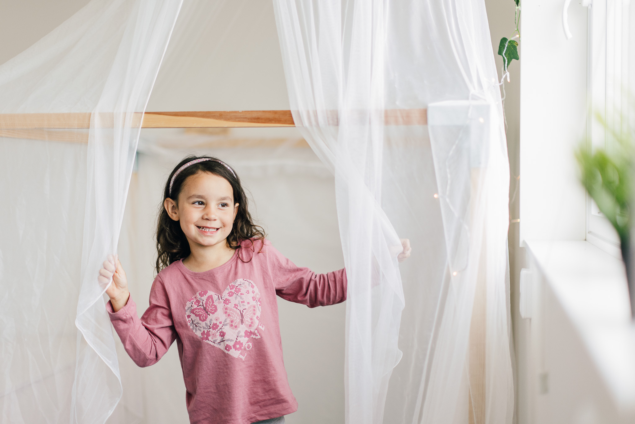 Glad flicka på Hamre förskola i Västerås, hon håller i nätgardinoch tittar ut genom fönstret