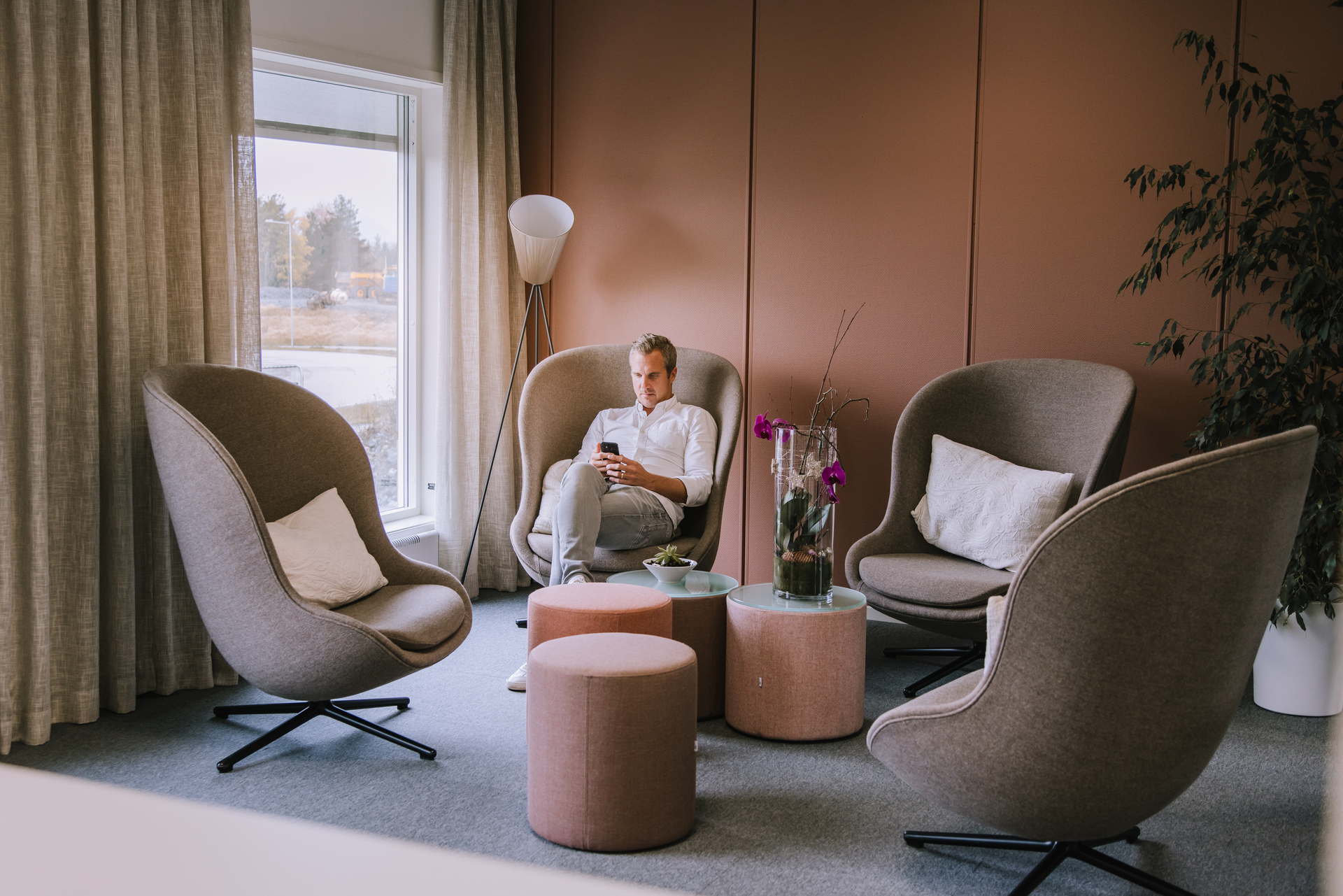 man sitter med mobil i trivsamt inredd kontorsmodul