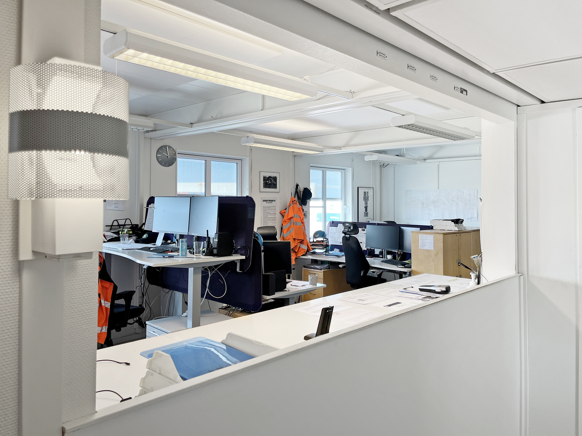 Kök i moduler med vita skåp, rostfri dubbel diskho, kaffebryggare och vattenkokare, rött kakel som stänkskydd samt fönster med dagsljus.