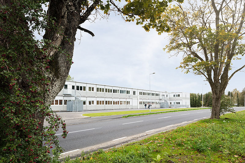 Översiktsvy av skolans modullösning från Expandia vid Kronängsskolan i Borås, placerad längs en gata och omgiven av grönska, med ljusa moduler i två plan anpassade för tillfälliga skolbehov.