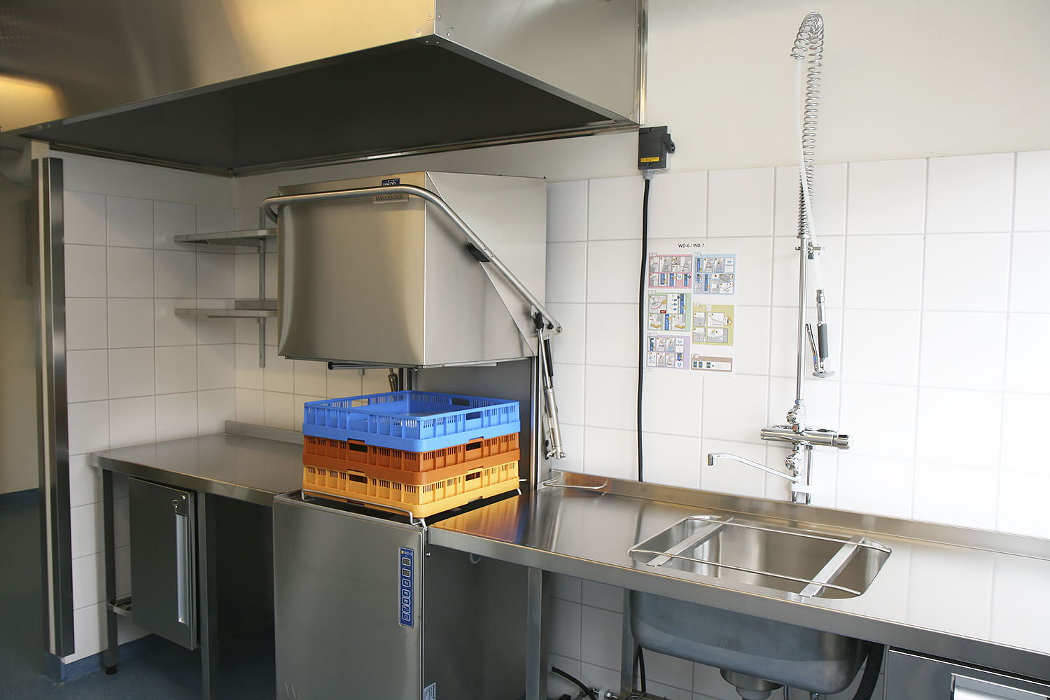 Disk- och rengöringsstation i storkök vid Hultsbergsskolan i Karlstad, med industriell diskmaskin, rostfri diskbänk och spolhandtag, placerad i en skolmodul från Expandia.