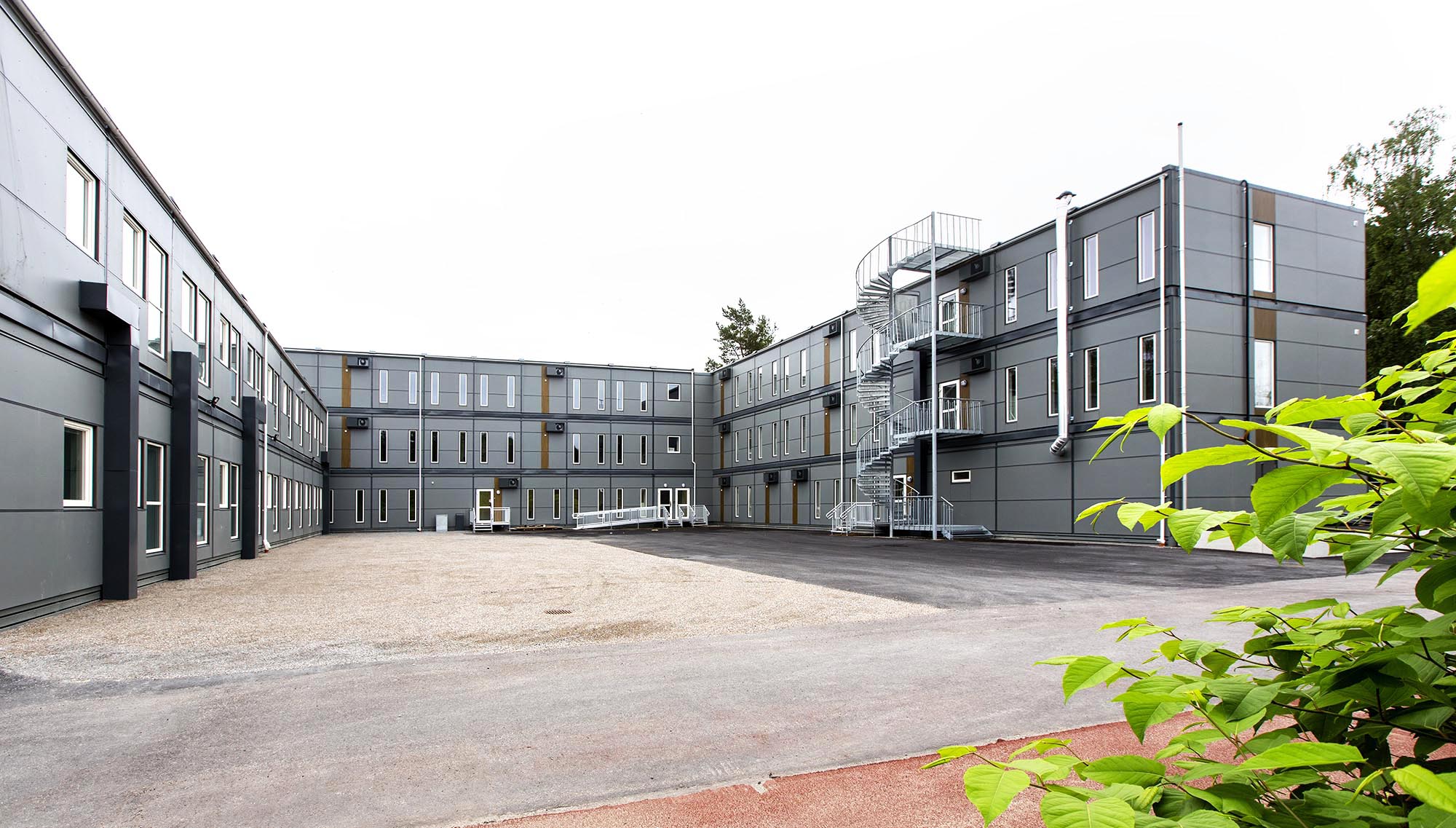 Exteriör vy av Falkbergsskolans modullösning i Tullinge med flera sammankopplade våningsplan, innergård och spiraltrappa – en modern och flexibel skolmodullösning från Expandia.