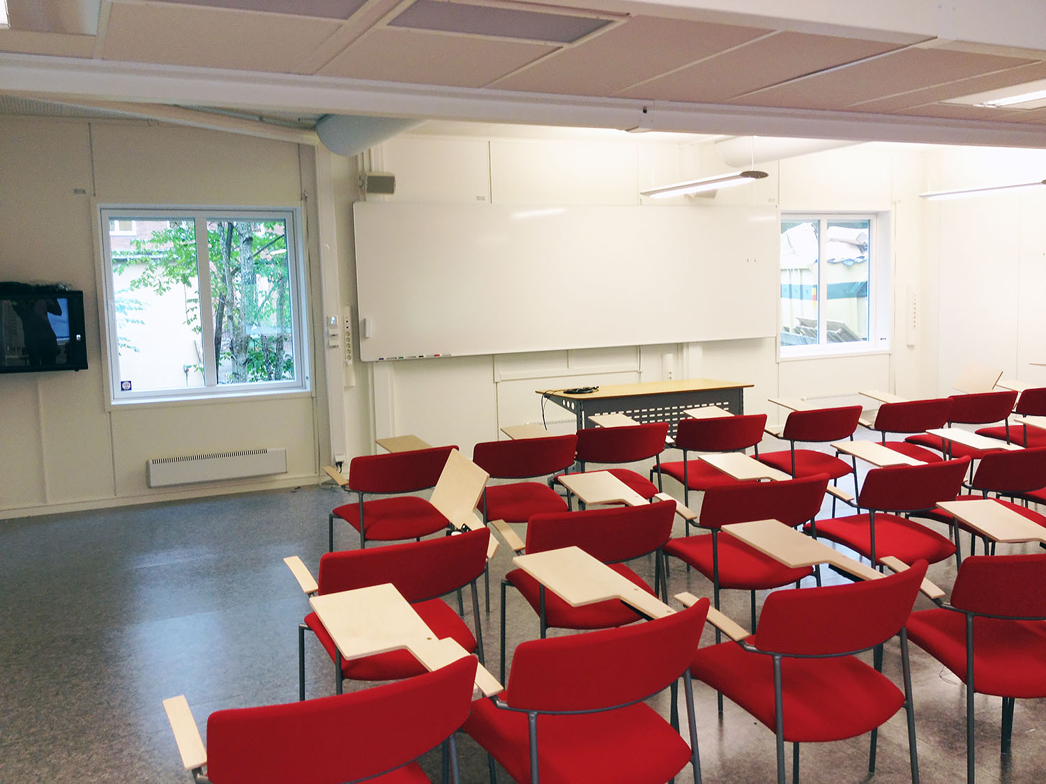 Utbildnings- och möteslokal i kontorsmodul med röda stolar och skrivbord, whiteboard, presentationsyta och stora fönster som ger bra ljusinsläpp – flexibla moduler från Expandia.