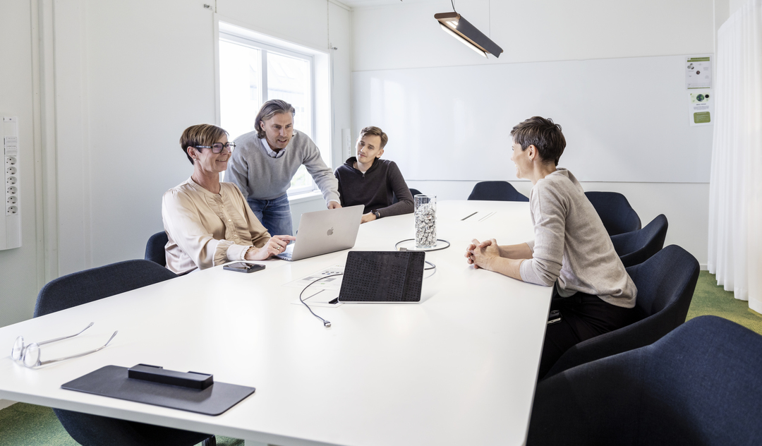 Mötes- och arbetsrum i kontorsmoduler hos Polypeptide med medarbetare som samarbetar vid bord och datorer, utrustade med skärmar, whiteboard, glaspartier, grön heltäckningsmatta och modern belysning i en ljus och funktionell kontorsmiljö – kontorsmoduler från Expandia.
